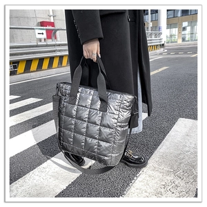 Detailed view of silver quilted tote bag with metallic texture and black shoulder strap