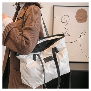Detailed close-up of a quilted tote bag featuring a leather fashion label and black straps