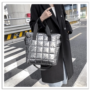 Street style view of a silver quilted puffer tote bag with black nylon straps