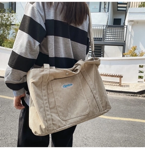 Detail of beige corduroy tote bag showing large capacity, dual handles and blue embroidery