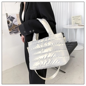 Detail view of a white quilted puffer bag featuring a glossy finish and long shoulder strap