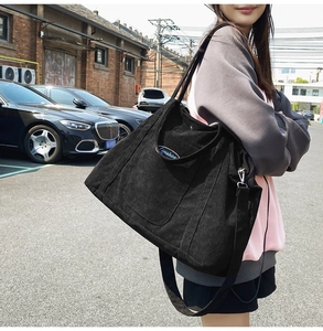 Detail of a large black corduroy tote bag showing its texture and adjustable shoulder strap