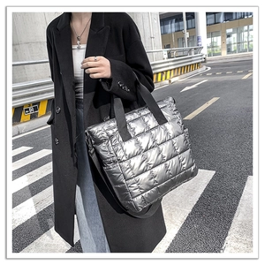 Detail of silver quilted tote bag with urban street style showing crossbody strap
