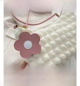 Détail du tissu blanc texturé pop-corn du sac avec pendentif floral rose et sangle