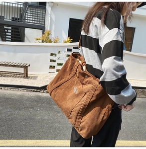 Detail view of large brown corduroy tote bag with soft texture and embroidered logo