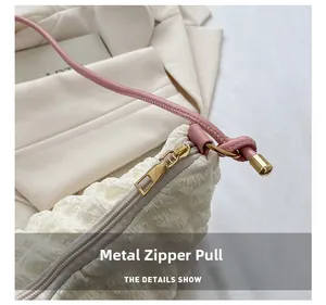 Gros plan sur la texture plissée blanche avec zip doré et détails de bandoulière rose