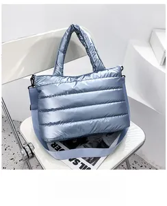 Detail of light blue metallic quilted tote bag with padded handles and long strap