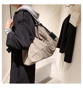Side view of khaki large capacity tote bag with pleated crescent design on a fashion model