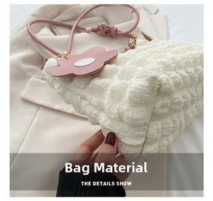 Détail du sac à main plissé crème avec bandoulière rose et breloque fleurie élégante