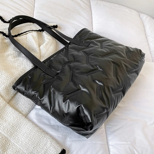 Minimalist black quilted tote bag with glossy finish and wide straps for daily commute
