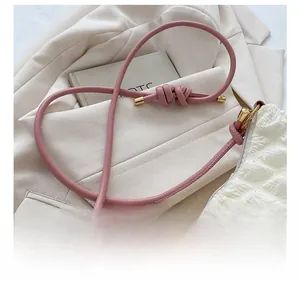 Détail du sac bandoulière blanc plissé avec bandoulière en cuir rose nouée et embouts en métal