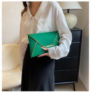 Détail de la pochette enveloppe verte à texture crocodile avec accents métalliques dorés