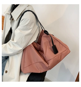 Detail of a large capacity dusty pink tote bag with black leather straps and smooth fabric