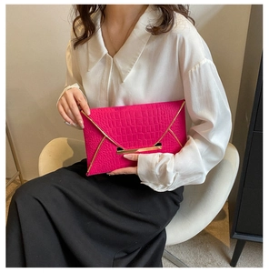 Vue macro d'une pochette magenta gaufrée crocodile avec détails en métal doré luxueux