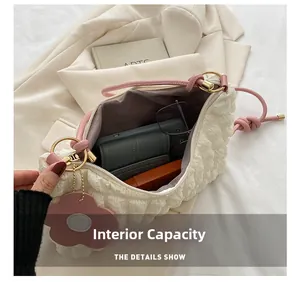 Vue détaillée de l'intérieur du sac crème texturé avec téléphone et accessoires