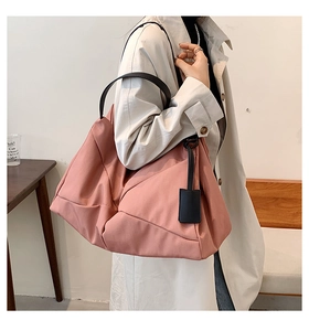 Detailed view of a spacious pink nylon shoulder bag with black handles on a model