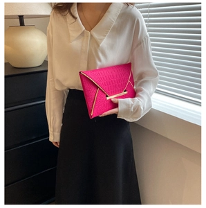 Détail de la pochette enveloppe rose fuchsia avec motif croco et garniture dorée