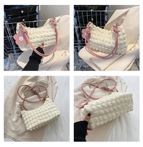 Détails d'un sac crème à texture gaufrée avec des poignées roses et un pendentif