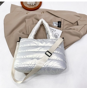 Close-up of silver quilted crossbody bag with adjustable white strap on a blazer