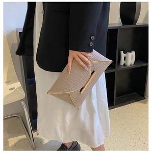 Détail de la pochette enveloppe beige embossée crocodile avec bordure en métal doré chic