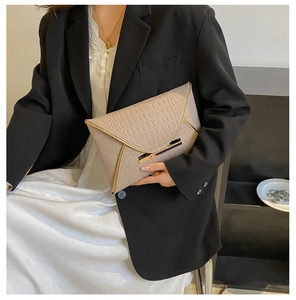 Détail de la pochette enveloppe beige avec motif crocodile et bord doré