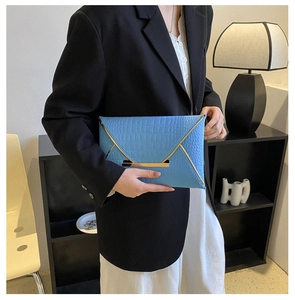 Gros plan d'une pochette enveloppe bleue à motif crocodile avec garniture dorée chic