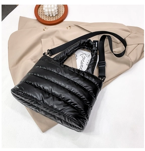 Detail view of glossy quilted puffer bag with removable wide nylon shoulder strap
