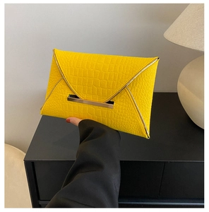 Détail d'une pochette enveloppe jaune vif avec texture crocodile et garniture dorée