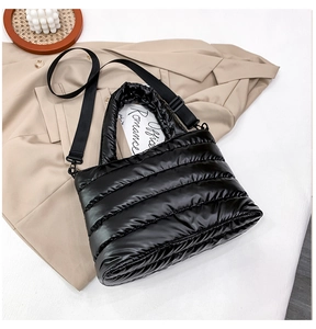 Close-up of quilted puffer bag with glossy finish and detachable fabric crossbody strap