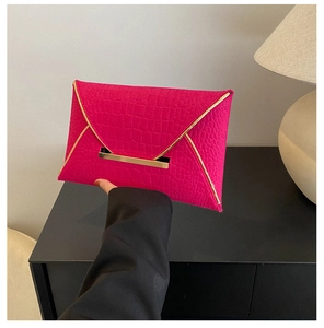 Détail d'une pochette enveloppe rose avec texture crocodile et finitions métalliques dorées