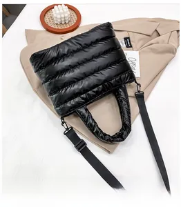 Detail of black quilted puffer bag with glossy finish and adjustable textile shoulder strap