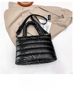 Detail shot of black quilted puffer tote bag with adjustable shoulder strap on suit