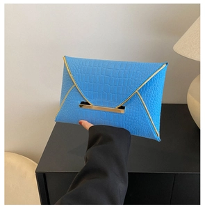 Détail de la pochette enveloppe bleu ciel avec texture crocodile et bordure dorée