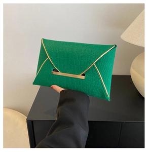 Détail de la pochette enveloppe verte à texture croco et garniture dorée en V