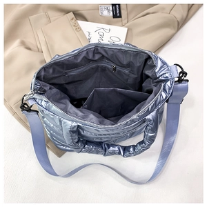 Macro shot showing internal zip pocket and open slot of metallic blue quilted bag