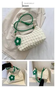 Détail du sac beige à texture bulles avec bandoulière verte et pendentif floral