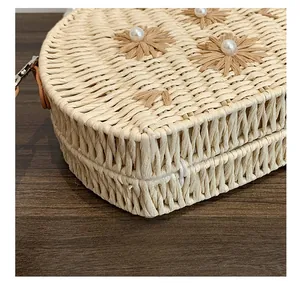 Vue détaillée du sac en paille tissé à la main avec motifs floraux et perles blanches