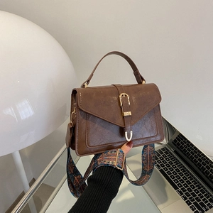 Vintage brown leather crossbody bag with gold horseshoe buckle and colorful woven strap