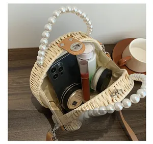 Détail de l'intérieur du sac en paille contenant téléphone, rouge à lèvres et poudre