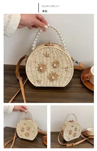 Détail du sac rond en paille avec anse en perles, fleurs tissées et bandoulière en cuir