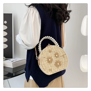 Détail du sac en paille tressée avec fleurs décoratives et anse élégante en perles