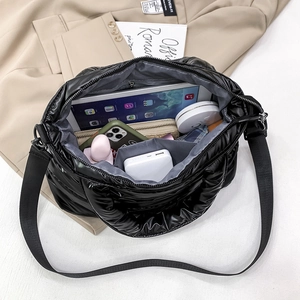 Black quilted puffer crossbody bag showing spacious interior with tablet and accessories