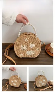 Détail du sac rond en paille kaki avec poignée en perles et fleurs 3D blanches