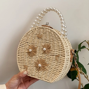 Sac à main rond en paille beige avec anse en perles et détails floraux pour vacances