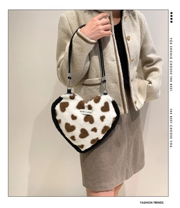 Close-up of heart-shaped faux fur bag with white and brown patterns and black leather strap