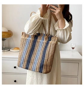 Dettaglio della borsa tote in paglia con strisce blu verticali e bordi con frange