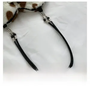 Detail view of cow print plush bag with black leather handle and silver metal buckle