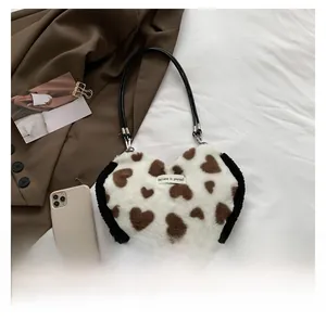 Detail view of heart-shaped faux fur shoulder bag with white plush texture and brown prints