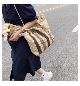 Borsa a spalla in paglia a righe verticali con frange mostrata in un ambiente esterno chic