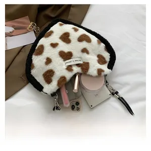 Detail view of heart-shaped plush bag showing interior space for phone and makeup items